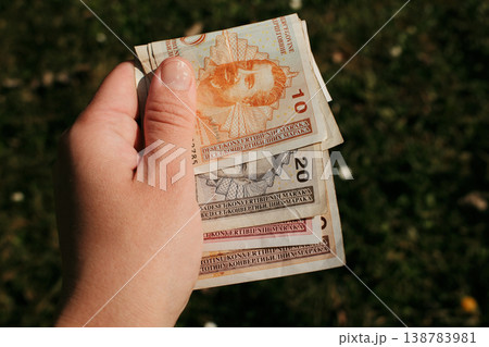 Hand holding several Bosnia and Herzegovina convertible mark banknotes outdoors over grass background. Concept of cash money, Balkan currency, financial transactions and personal budgeting Hand holding several Bosnia and Herzegovina convertible mark banknotes outdoors over grass background. Concept of cash money, Balkan currency, financial transactions and personal budgeting 138783981