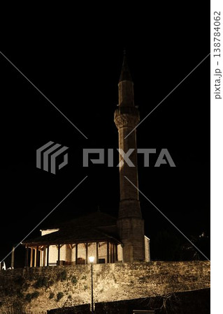 Night view of a mosque with illuminated minaret beside stone residential buildings in Mostar under a dark sky Night view of a mosque with illuminated minaret beside stone residential buildings in Mostar under a dark sky 138784062