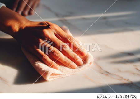 A hand is seen wiping a surface with a cloth in warm natural light during a cleaning session in the afternoon A hand is seen wiping a surface with a cloth in warm natural light during a cleaning session in the afternoon 138784720