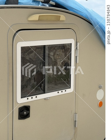 Camper door with broken window covered by blue tarp, damage concept in outdoor setting Camper door with broken window covered by blue tarp, damage concept in outdoor setting 138784843