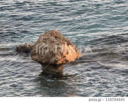 Rock formation in ocean with rippling water and gentle waves creating a serene background Rock formation in ocean with rippling water and gentle waves creating a serene background 138784845