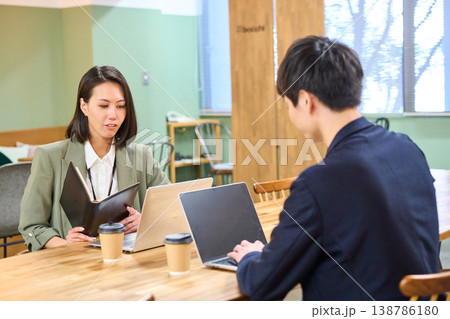 コワーキングスペースで手帳を開き真剣に打ち合わせをする女性社員 コワーキングスペースで手帳を開き真剣に打ち合わせをする女性社員 138786180