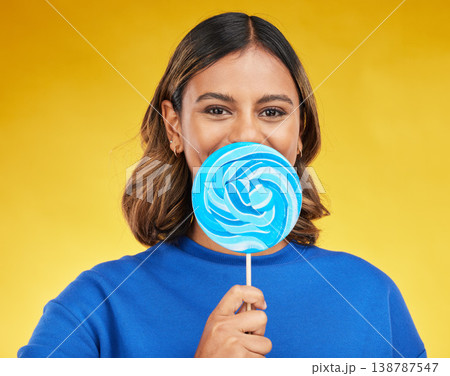Lollipop, candy and portrait of woman with sweet dessert with sugar isolated in a studio yellow background with smile. Food, snack and young person with delicious treats, product or guilty pleasure 138787547