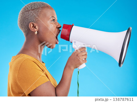 Black woman, megaphone and shout in studio, protest and profile with noise for human rights by blue background. African gen z student, girl and audio tech for justice, opinion or news announcement Black woman, megaphone and shout in studio, protest and profile with noise for human rights by blue background. African gen z student, girl and audio tech for justice, opinion or news announcement 138787611