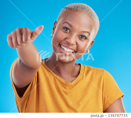 Black woman, thumbs up and studio portrait with smile for feedback, review and winning by blue background. Gen z African girl, student and happy with icon, sign language and choice with yes for promo Black woman, thumbs up and studio portrait with smile for feedback, review and winning by blue background. Gen z African girl, student and happy with icon, sign language and choice with yes for promo 138787735