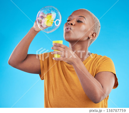 African, woman and blowing bubbles in studio, blue background or party celebration with fun, liquid soap or toy. Black model, person and relax with happy, joyful or creative play for enjoyment African, woman and blowing bubbles in studio, blue background or party celebration with fun, liquid soap or toy. Black model, person and relax with happy, joyful or creative play for enjoyment 138787759