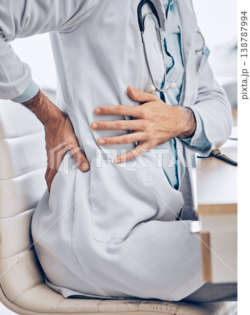 Man, doctor and hands with back pain from injury, accident or posture sitting on chair at the hospital. Closeup of male person, medical or healthcare employee with sore spine, ache or cramp at clinic Man, doctor and hands with back pain from injury, accident or posture sitting on chair at the hospital. Closeup of male person, medical or healthcare employee with sore spine, ache or cramp at clinic 138787994