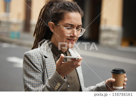 Business woman on voice message in a city to travel or commute in the morning with coffee talking to contact. Online, hipster and employee walking speaking or networking with cellphone on internet Business woman on voice message in a city to travel or commute in the morning with coffee talking to contact. Online, hipster and employee walking speaking or networking with cellphone on internet 138788161