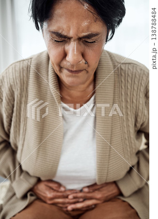 Stomach pain, sick or illness with a senior woman in her home, holding her belly in discomfort. Healthcare, medical and emergency with an elderly pensioner feeling uncomfortable after food poisoning 138788484