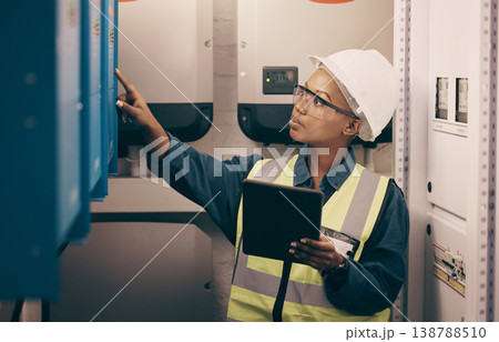 Engineering, black woman or electrician on tablet for maintenance, server or machine board system. Female technician, digital technology or electrical mechanic in control room at industrial power box 138788510