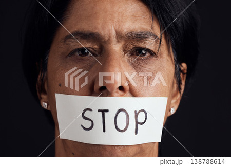 Portrait, stop and silence with a woman in studio on a black background for gender equality or domestic violence. Face, censorship or abuse and a scared female victim with her mouth covered closeup Portrait, stop and silence with a woman in studio on a black background for gender equality or domestic violence. Face, censorship or abuse and a scared female victim with her mouth covered closeup 138788614