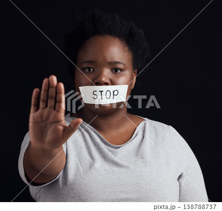 Portrait, stop and palm with a black woman in studio on a black background for gender equality or domestic violence. Hand, silence or abuse and a scared female victim with her mouth covered in fear Portrait, stop and palm with a black woman in studio on a black background for gender equality or domestic violence. Hand, silence or abuse and a scared female victim with her mouth covered in fear 138788737
