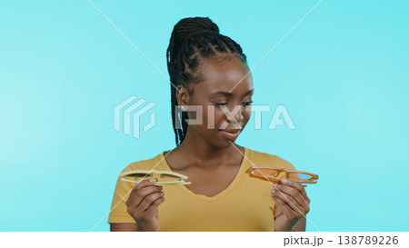 Woman, glasses and fashion choice or decision in studio by blue background, shopping and trendy accessories. Black female model, thinking and choose the sunglasses, frame and cool design in mockup 138789226