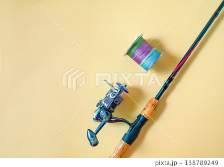 Fishing rod spinning with the line on color background. Fishing rod spinning with the line on color background. 138789249