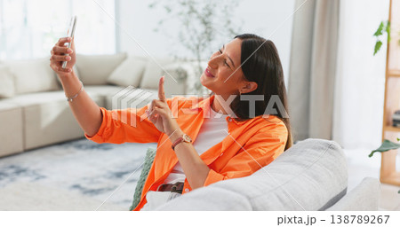 Happy, selfie and woman on sofa in living room, home or relax in apartment with peace on social media and app. Influencer, smile and post happiness online of photography on couch in house lounge Happy, selfie and woman on sofa in living room, home or relax in apartment with peace on social media and app. Influencer, smile and post happiness online of photography on couch in house lounge 138789267