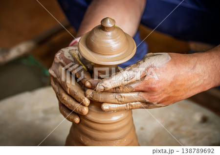 Skilled artisan hands shaping wet clay on a spinning potter wheel, creating a ceramic vase in a traditional pottery workshop. Skilled artisan hands shaping wet clay on a spinning potter wheel, creating a ceramic vase in a traditional pottery workshop. 138789692