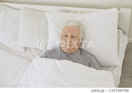 Senior man with insomnia sleeping disorder lying awake in bed staring at ceiling Senior man with insomnia sleeping disorder lying awake in bed staring at ceiling 138789788