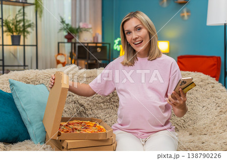 Pregnant woman paying pizza order with banking app card taps smartphone excited for big tasty dinner Pregnant woman paying pizza order with banking app card taps smartphone excited for big tasty dinner 138790226