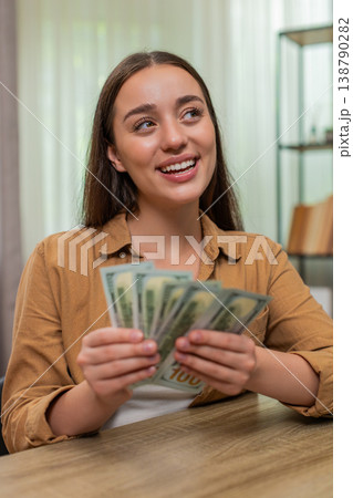 Young woman counting money dollars cash satisfied with salary earnings celebrating financial success Young woman counting money dollars cash satisfied with salary earnings celebrating financial success 138790282