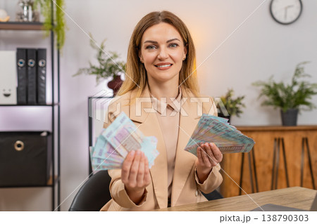 Rich businesswoman counts money hryvnia cash amazed by high salary income bonus rise profit stack Rich businesswoman counts money hryvnia cash amazed by high salary income bonus rise profit stack 138790303