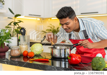 Indian man cooking homemade soup in kitchen for healthy meal prep and clean eating routine at home Indian man cooking homemade soup in kitchen for healthy meal prep and clean eating routine at home 138790391