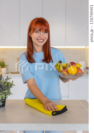 Young woman wipes kitchen countertop with microfiber cloth polishes surface shows clean tidy order Young woman wipes kitchen countertop with microfiber cloth polishes surface shows clean tidy order 138790401