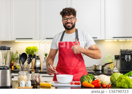 Arabian young adult man whisking eggs in home kitchen preparing omelet batter for healthy meal prep Arabian young adult man whisking eggs in home kitchen preparing omelet batter for healthy meal prep 138790723