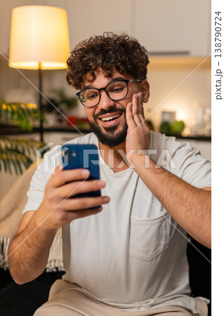 Arabian man celebrates online game jackpot win after good news alert on smartphone at night indoors 138790724