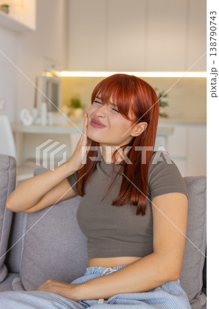 Young woman with toothache holds cheek frowns in pain seeks dentist help and relief urgent care aid Young woman with toothache holds cheek frowns in pain seeks dentist help and relief urgent care aid 138790743