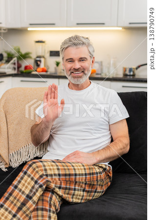 Middle-aged man waves to camera smiles hello online connection greets viewer friendly positive mood 138790749