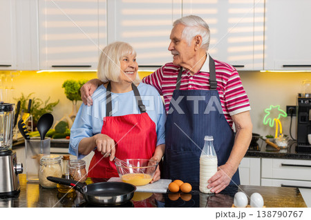 Senior old woman man cooking healthy omelet breakfast in home kitchen with cheerful elderly couple Senior old woman man cooking healthy omelet breakfast in home kitchen with cheerful elderly couple 138790767