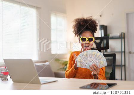 Young African American woman with surprised expression holding bunch of hundred dollar bills Young African American woman with surprised expression holding bunch of hundred dollar bills 138791331