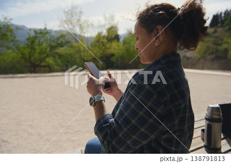 Woman using smartphone outdoors with mountain landscape, digital lifestyle concept Woman using smartphone outdoors with mountain landscape, digital lifestyle concept 138791813