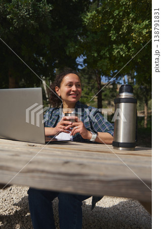 Woman with coffee cup and thermos working outdoors Woman with coffee cup and thermos working outdoors 138791831