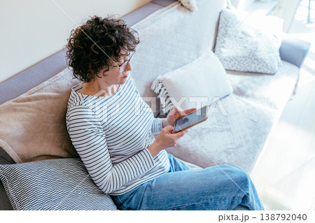 White woman in her 40s looking at smartphone screen, focused expression, checking information, digital lifestyle, home routine, indoor casual moment, modern communication White woman in her 40s looking at smartphone screen, focused expression, checking information, digital lifestyle, home routine, indoor casual moment, modern communication 138792040