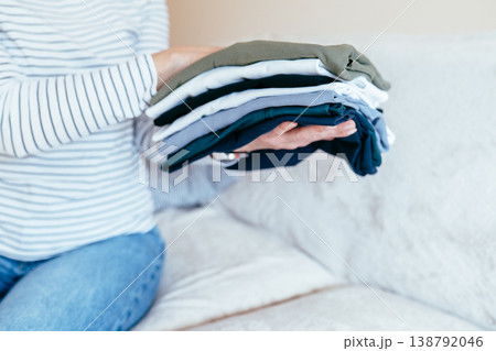 Female hands holding stack of folded clothes in neutral colors, organized wardrobe, textile care, home routine, neat arrangement, minimal lifestyle, everyday clothing management Female hands holding stack of folded clothes in neutral colors, organized wardrobe, textile care, home routine, neat arrangement, minimal lifestyle, everyday clothing management 138792046