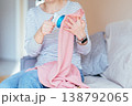 Close up female hands using electric fabric shaver on pink knitwear. Unrecognizable woman removing pills from textile, clothing care routine, home maintenance, soft fabric detail. 138792065