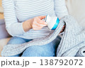 Close up of unrecognizable woman in striped shirt using fabric shaver on gray knitted sweater while sitting at home. Domestic clothing care, garment maintenance, pilling removal, cozy everyday routine 138792072
