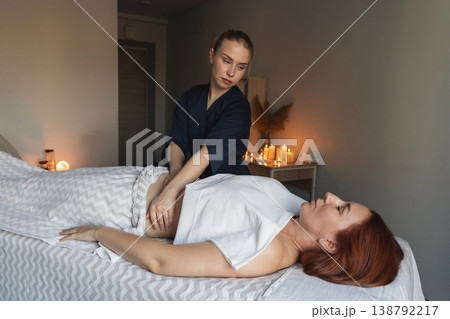 Woman receiving relaxing stomach massage from a therapist in a tranquil spa room with warm candlelight. Promoting wellness and health Woman receiving relaxing stomach massage from a therapist in a tranquil spa room with warm candlelight. Promoting wellness and health 138792217