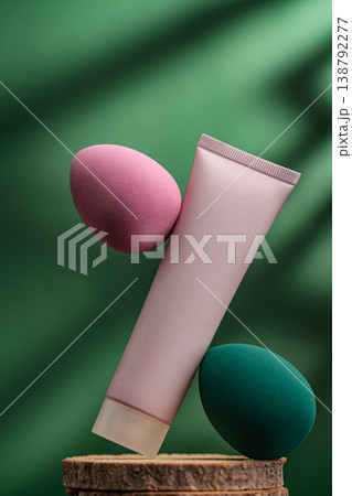 Cosmetic tube and beauty sponge on natural wooden stand with green background 138792277