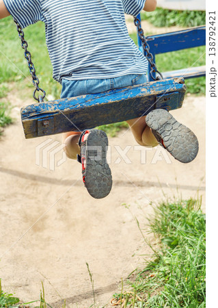 Boy swinging peacefully in sunny park. Young boy enjoying carefree moment swinging in sunlit park Boy swinging peacefully in sunny park. Young boy enjoying carefree moment swinging in sunlit park 138792421