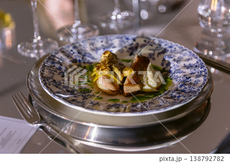 Gourmet main course with meat and sauce served on decorative plate in dining restaurant 138792782