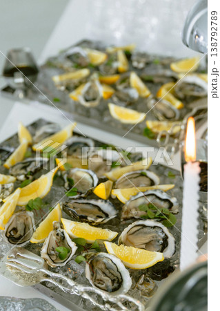 Oysters served on ice with lemon slices at elegant seafood reception. Oysters served on ice with lemon slices at elegant seafood reception. 138792789