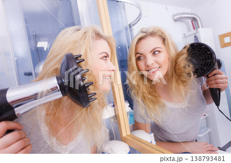 Woman doing curls with hairdryer diffuser 138793481