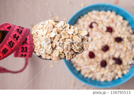 Oatmeal in bowl and measuring tape around spoon 138793513