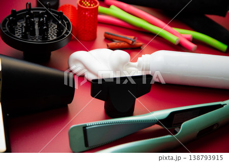 Close-up side view on a pink background, hairdryer with attachments, stylers and curling irons for straightening and creating curls, foam for volume and long-lasting, curlers in different shapes and Close-up side view on a pink background, hairdryer with attachments, stylers and curling irons for straightening and creating curls, foam for volume and long-lasting, curlers in different shapes and 138793915