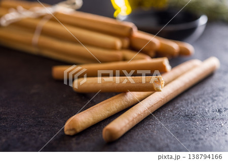 Bundled Italian Breadsticks (Grissini) with Olive Oil and Rosemary on Dark Surface Bundled Italian Breadsticks (Grissini) with Olive Oil and Rosemary on Dark Surface 138794166