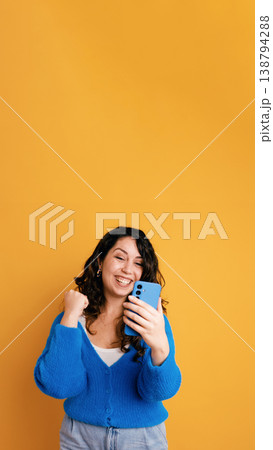 Excited woman celebrating victory holding smartphone Excited woman celebrating victory holding smartphone 138794288