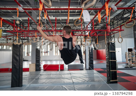 An athletic man practices at a ninja club's indoor obstacle course. 138794298