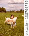 Girl cradling a baby goat in her arms, surrounded by a lush green field, basking in the warmth of a sunny day 138794739